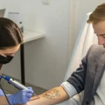 A person receiving tattoo removal treatment on their forearm in preparation for a job interview, in the USA with a résumé visible on the table.